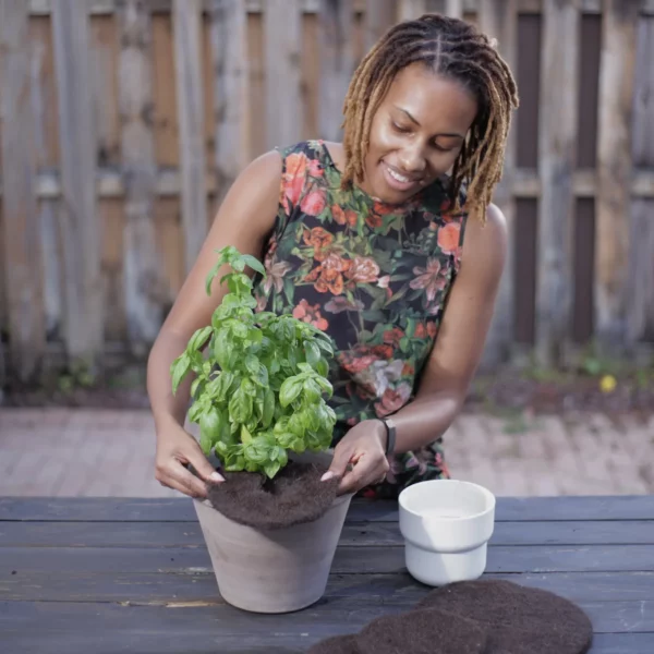 woman using a Smart4Growing BioMat around a potted plant