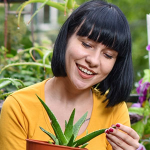 woman smiling while looking at the leaf of a plant